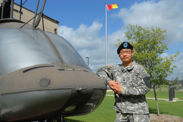 FORT HOOD, Texas - Spc. Cecil Wong, from Dallas, a paralegal specialist for 1st Air Cavalry Brigade, 1st Cavalry Division, pauses next to a Kiowa helicopter in front of the 1st ACB's headquarters building, here, July 15. Wong, who recently...