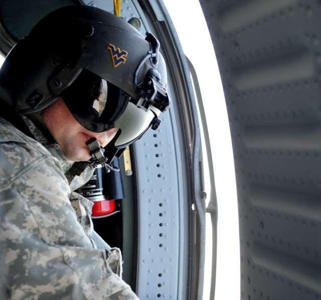 U.S. Army Sgt. Richard Kyle, UH-60 Black Hawk crew member, monitors passengers during a U.S. Air Force Academy Wings of Blue Jump Team demonstration run July 25. The team will perform at the Boy Scouts of America’s 2010 National Scout Jamboree, runni...