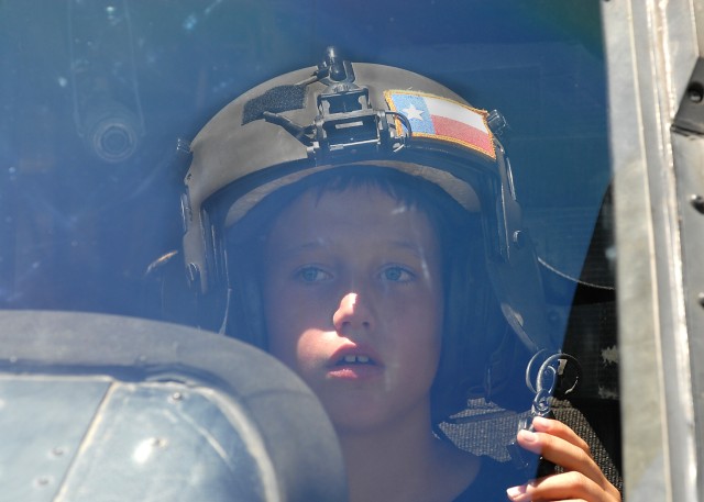KILLEEN, Texas - Dolton Thibodeaux, 10, from Belton, Texas tries on a pilot helmet while sitting in the crewstation of a Black Hawk helicopter, during a visit from a flight crew from Company C, 3rd Assault Helicopter Battalion, 227th Aviation...