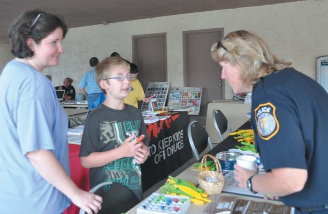 Patriot Village residents Laura Cooper and her son Daren, 9, chat with Directorate of Emergency Services Police Officer Nicole Hall at the Crime Prevention Unit display table during National Night Out 2010 activities at the Community Policing...