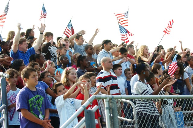 FORT HOOD, Texas- Staff and students wave flags and their hands and arms as they sing Lee Greenwood's "God Bless the U.S.A." during a 9/11 Memorial Ceremony, sponsored by the 1st Battalion, 8th Cavalry Regiment, 2nd Brigade Combat Team, 1st Cavalry D...