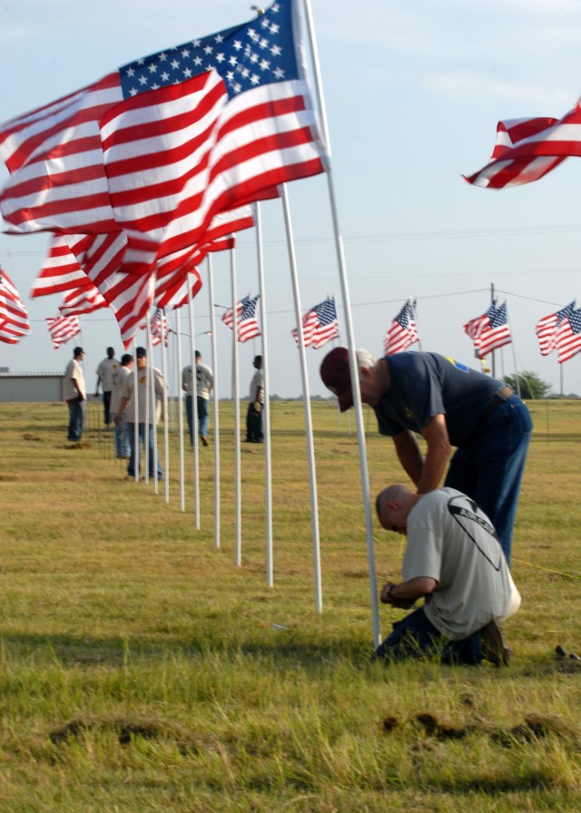 KILLEEN, Texas-A Soldier (kneeling) from 1st Air Cavalry Brigade, 1st Cavalry Division, and a member of the Patriot Guard help put up American flags for the Field of Honor display, part of the American Veterans Traveling Tribute, at the Killeen Civic...