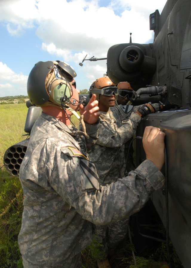FORT HOOD, Texas - Sergeant Roderick Rhodes (center), a squad leader from Dallas, trains Spc. Samba Sima (back), from Mali, West Africa to fuel an AH-64D Apache attack helicopter while Sgt. Sean McConnell (front), a pad chief from Columbus, Ohio, tal...