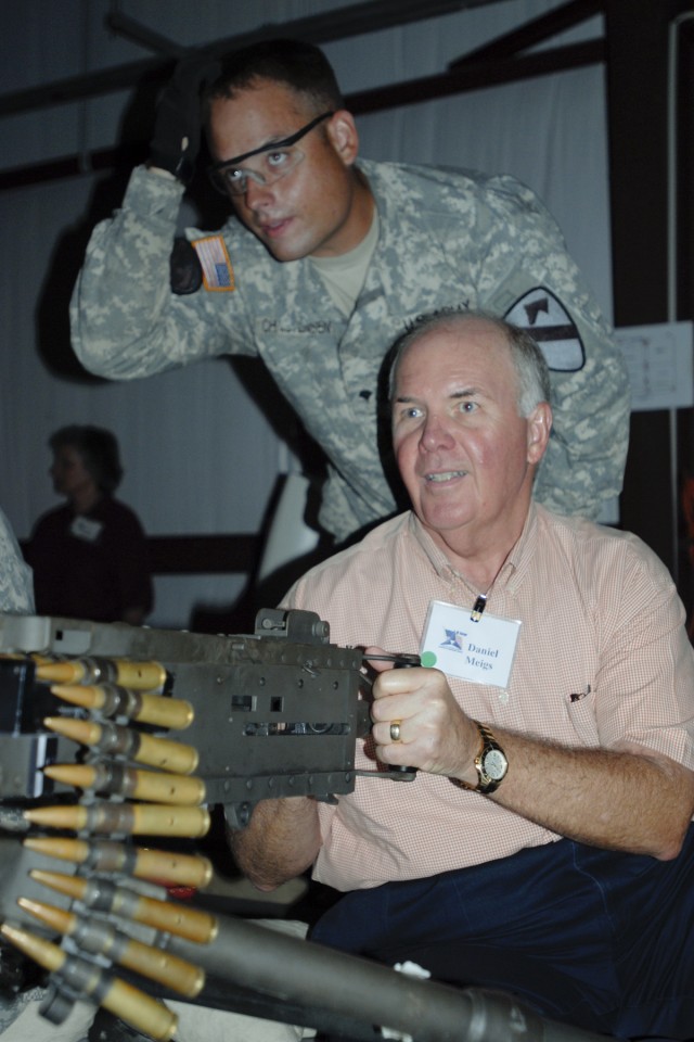 FORT HOOD, Texas-Spc. Jason Christenson, with 3rd Brigade Combat Team, 1st Cavalry Division, assists Councilman Dan Meigs, from Copperas Cove, Texas, in firing a .50 caliber automatic machine gun as part of a Central Texas Community Leader's Day,...