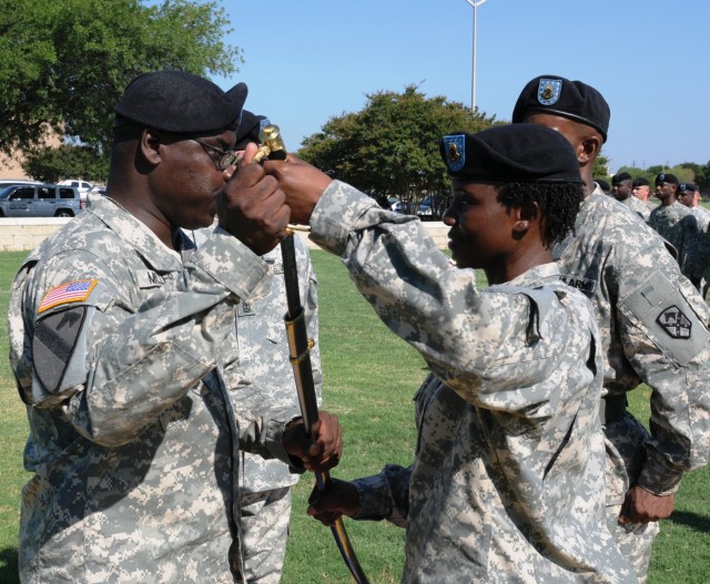 First Sergeant Jeanette Short, the outgoing senior noncommissioned officer for the Headquarters and Headquarters Company, Special Troops Battalion, 15th Sustainment Brigade, passes the saber to Command Sgt. Maj. Clarence Miller, the battalion's...