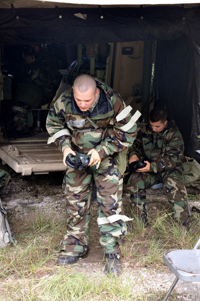 FORT HOOD, Texas - Spc. Jayme-Michael Hensley, native of Flint. Mich., Battery C, 2nd Battalion, 20th Field Artillery Regiment, 41st Fires Brigade, prepares to don his protective mask in a chemical attack during the Table XV battery level training...