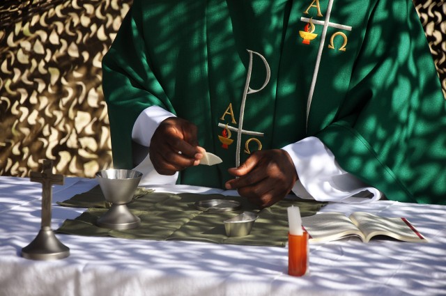 FORT HOOD, Texas-Chaplain (1st Lt.) Thomas Obiatuegwu, of Nigeria, breaks bread for Communion while delivering his first field Mass to Soldier in the 41st Fires Bde., Sept. 24. Obiatuegwu served as a civilian Catholic priest for six years in...