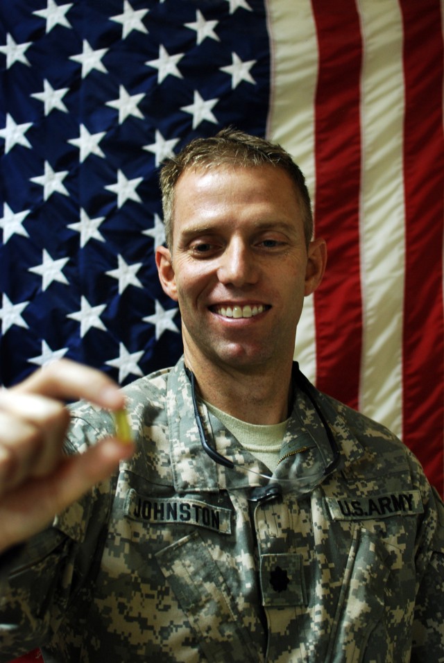 Lt. Col. Daniel Johnston, an Army doctor serving in Iraq with the Enhanced Combat Aviation Brigade, 1st Infantry Division, holds up an omega-3 capsule. Johnston received approval from an Army medical review board to conduct a study in Iraq on whether...