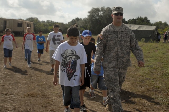 Staff Sgt. Matthew Eastwood, the Bradley Fighting Vehicle master gunner for 3rd Battalion, 8th Cavalry Regiment, 3rd Brigade Combat Team, 1st Cavalry Division, leads a group of elementary school children through one of Fort Hood's training areas...