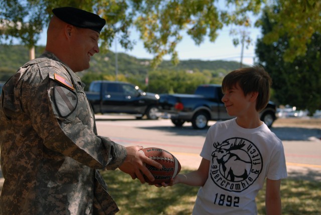 COPPERAS COVE, Texas - Brookville, Ind. native, Spc. Lee Jackson, a logistic specialist assigned to Headquarters and Headquarters Troop, 1st Brigade Special Troops Battalion, 1st Brigade Combat Team, 1st Cavalry Division, gives a football to a studen...