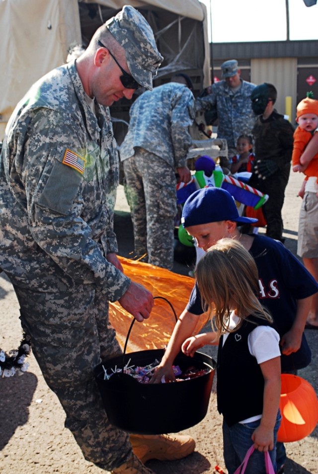 FORT HOOD, Texas- Spc. Jeff Quinn, from Portsmouth, N.H., a training room clerk for A Battery, 3rd Battalion, 82nd Field Artillery Regiment, 2nd Brigade Combat Team, 1st Cavalry Division, holds a bucket of candy while Jonathan and Lillian Phillips lo...