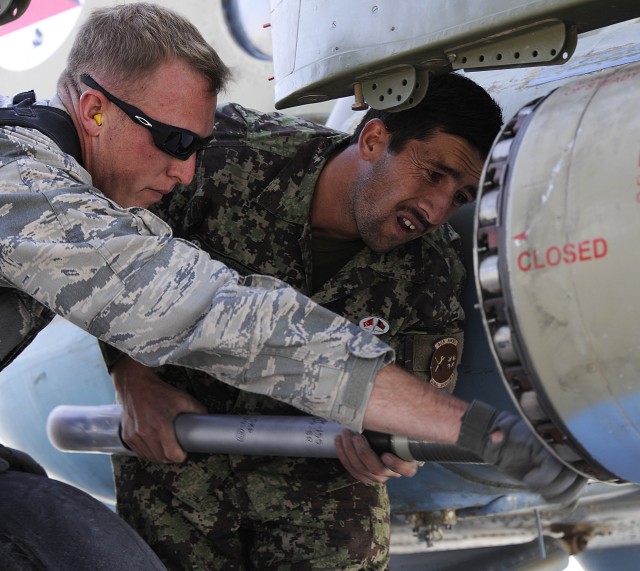 U.S. Airmen helps Afghan airmen load a rocket