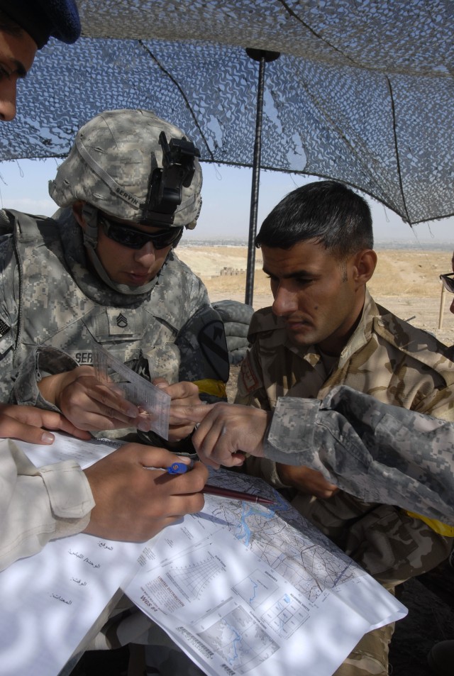 CONTINGENCY OPERATING SITE MAREZ, Iraq - Staff Sgt. Rodolfo Servin (left), a forward observer assigned to the 1st Squadron, 9th Cavalry Regiment, 4th Advise and Assist Brigade, 1st Cavalry Division, helps an Iraqi Army Soldier identify terrain...