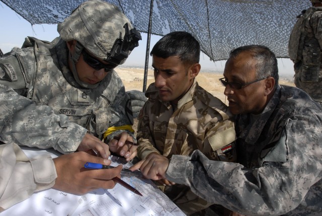 CONTINGENCY OPERATING SITE MAREZ, Iraq - Staff Sgt. Rodolfo Servin (left), a forward observer assigned to the 1st Squadron, 9th Cavalry Regiment, 4th Advise and Assist Brigade, 1st Cavalry Division, helps an Iraqi Army Soldier identify terrain featur...