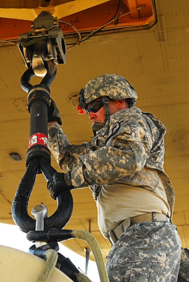 FORT HOOD, Texas- Spc. Robert Turrey, a fueler with Alpha Company, 15th Brigade Support Battalion, 2nd Brigade Combat Team, 1st Cavalry Division, attaches a rigging to the bottom of a CH-47 Chinook helicopter during sling load training on Fort Hood, ...