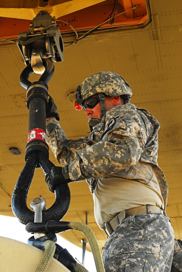 FORT HOOD, Texas- Spc. Robert Turrey, a fueler with Alpha Company, 15th Brigade Support Battalion, 2nd Brigade Combat Team, 1st Cavalry Division, attaches a rigging to the bottom of a CH-47 Chinook helicopter during sling load training on Fort...