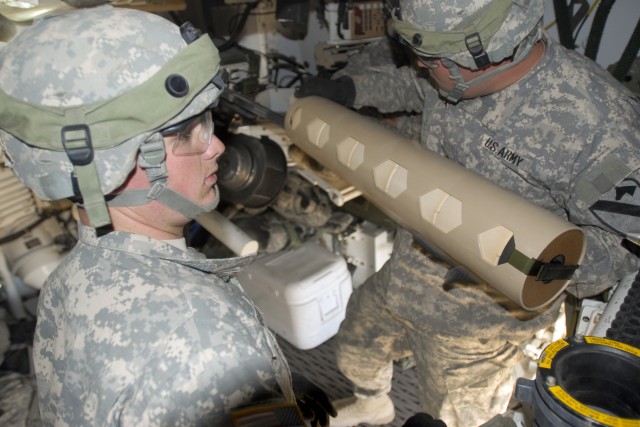 FORT IRWIN, Calif. - Pvt. Timothy Lambert (left) and Sgt. Justin Seaton, both cannon crewmembers with 2nd Battalion, 82nd Field Artillery Regiment, 3rd Brigade Combat Team, 1st Cavalry Division,  load charges into the tube of a M109A6 Paladin...