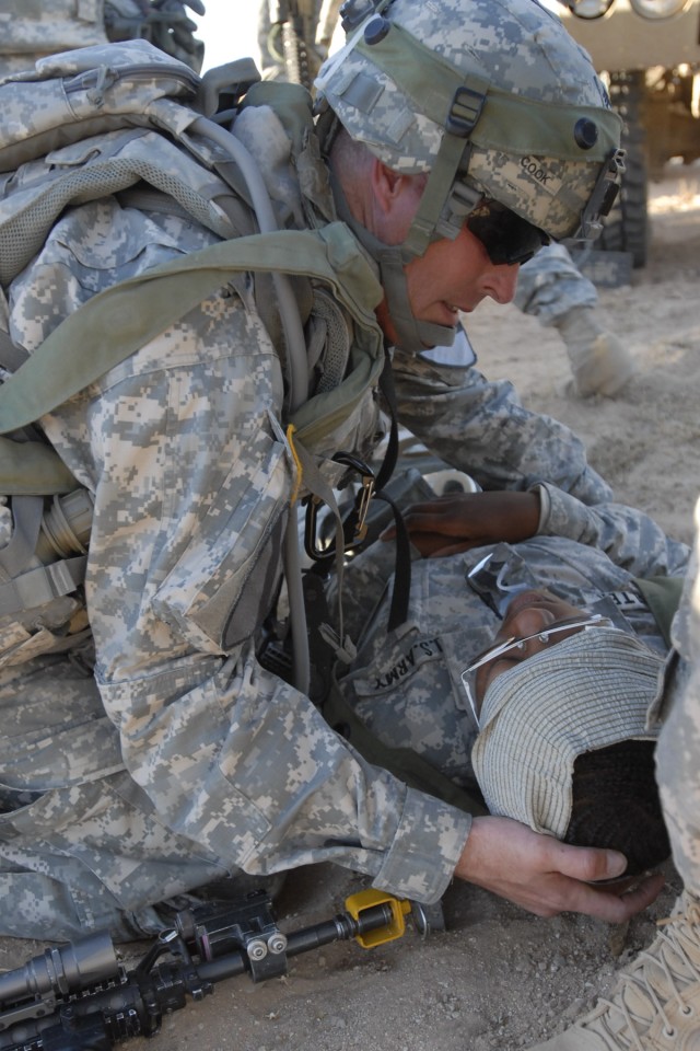 FORT IRWIN, Calif. -Sgt. 1st Class Glenn Cook, from Copperas Cove, Texas, provides first aid to Spc. Victoria Saulter, from Raleigh N.C., during a month-long training event at the National Training Center on Fort Irwin, Calif. to prepare the Soldiers...