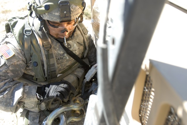 FORT IRWIN, Calif. - Sgt. 1st Class Salvador Zapata, a cavalry scout with B Troop, 6th Squadron, 9th Cavalry Regiment, 3rd Brigade Combat Team, 1st Cavalry Division, connects a tow cable to the front bumper of his humvee during a training exercise...