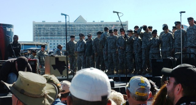 FORT WORTH, Texas- Soldiers from Headquarters and Headquarters Company, 2nd Brigade Combat Team, 1st Cavalry Division, along with other Soldiers, wait on stage for a performance from country music artist Willie Nelson at the Texas Motor Speedway, her...