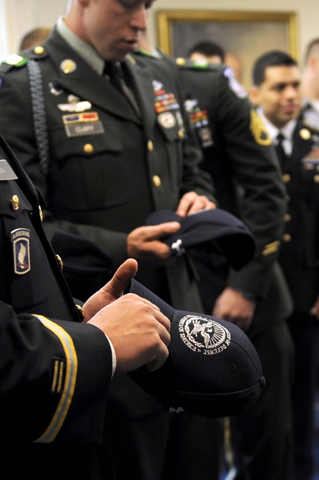 Defense Secretary Robert M. Gates gives out Secretary of Defense ball caps to Medal of Honor recipient Army Staff Sgt. Salvatore Giunta and the men of Company B, 2nd Battalion, Airborne, 503rd Infantry Regiment, during their visit to the Pentagon, No...
