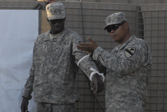 Sgt. Benjamin Jingco (right), a combat medic assigned to 2nd Battalion, 7th Cavalry Regiment, 4th Advise and Assist Brigade, 1st Cavalry Division, demonstrates on Pfc. Myron Macklin, from Petersburg, Va., how to properly splint a fractured arm at a c...
