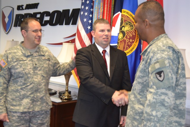 Retired Staff Sgt. Mitch Court receives U.S. Army Research, Development and Engineering Command coins from Deputy Commanding General Brig. Gen. Harry Greene, left, and Command Sgt. Maj. Hector Marin, who also presented Court with a camouflaged...