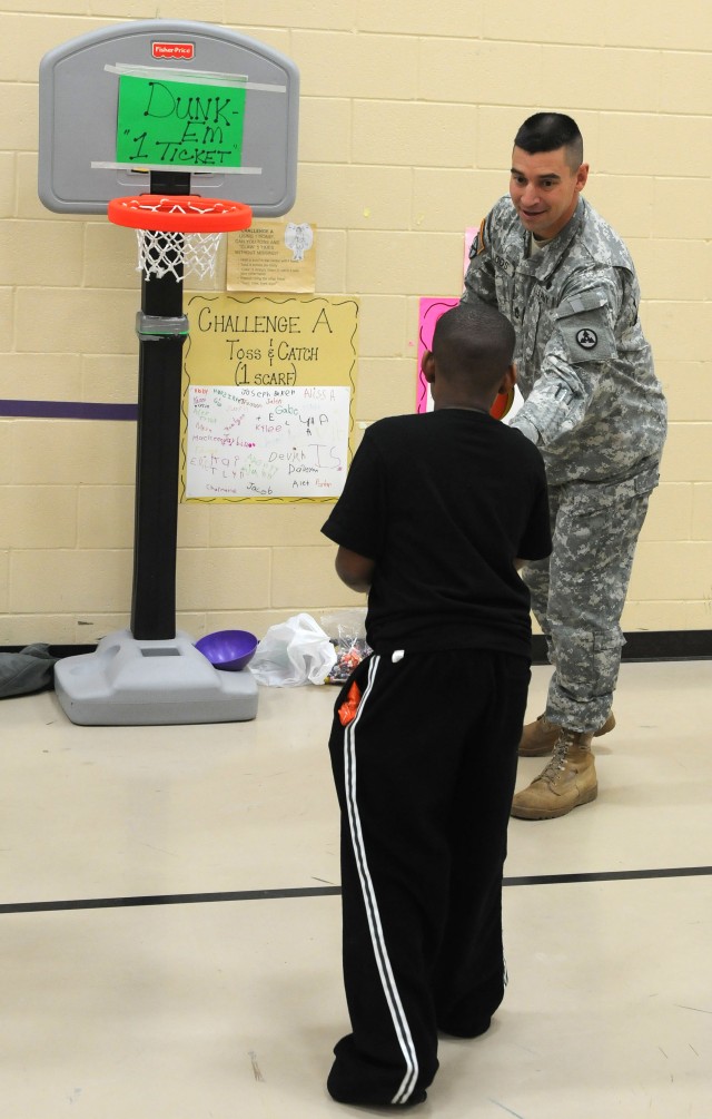 Sergeant 1st Class Aaron Loos, a maintenance management noncommissioned officer with the 3d Sustainment Command (Expeditionary), hands a basketball to a student during the Pierce Elementary School Winter Festival Dec. 2. Sergeant 1st Class Loos was o...
