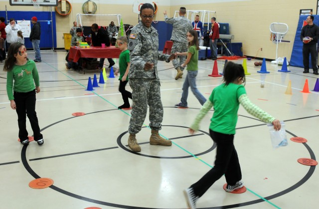Staff Sgt. Jacinta Bonner, a transportation control noncommissioned officer with the 3d Sustainment Command (Expeditionary), assists students with the cake walk, a game, similar to musical chairs, in which the winner gets a cake, Dec. 2 at Pierce Ele...