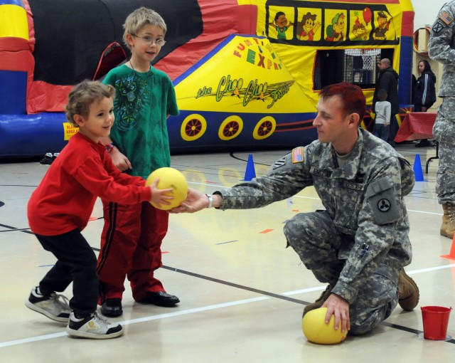 Sergeant 1st Class Andrew England, with the 3d Sustainment Command (Expeditionary), hands a bowling ball to a Pierce Elementary School student at the school's Winter Festival Dec. 2. Sergeant 1st Class England and about 24 other Soldiers from the...