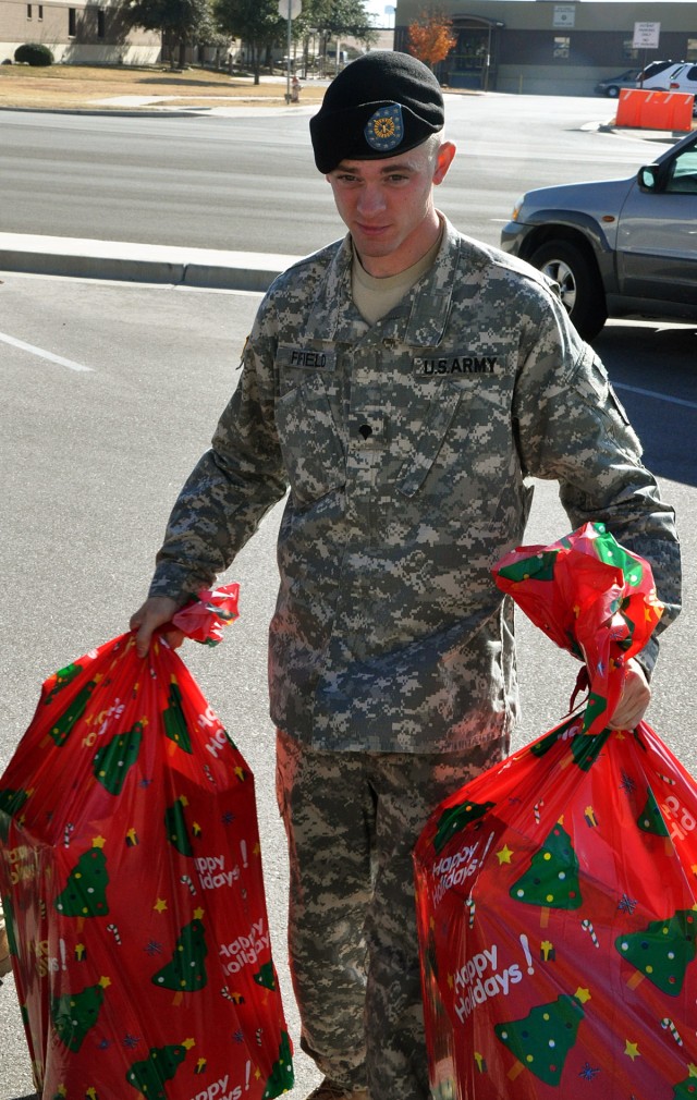 FORT HOOD, Texas-Spc. Jamie Fifield, an early warning systems operator for the Headquarters and Headquarters Battery, 41st Fires Brigade, carries bags of toys into the Charles B. Allen Hall where Leon County residents delivered more than 500 toys...