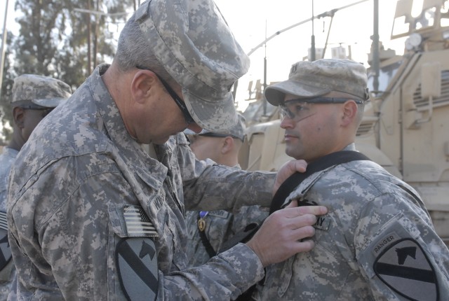 JOINT SECURITY STATION INDIA, Iraq-Col. Brian Winski (left), commander of 4th Advise and Assist Brigade, 1st Cavalry Division, pins a Combat Infantry Badge on Capt. Daron Moreno, the company commander for Company B, 2nd Battalion, 7th Cavalry...