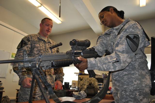 CONTINGENCY OPERATING SITE MAREZ, Iraq- Sgt. 1st Class Joseph Thomas (left), instructs Sgt. Tara Davis, of Savannah, Ga., how to clear a squad automatic weapon during the unit's safety stand down day, Dec. 23. Weapon safety and awareness is also...