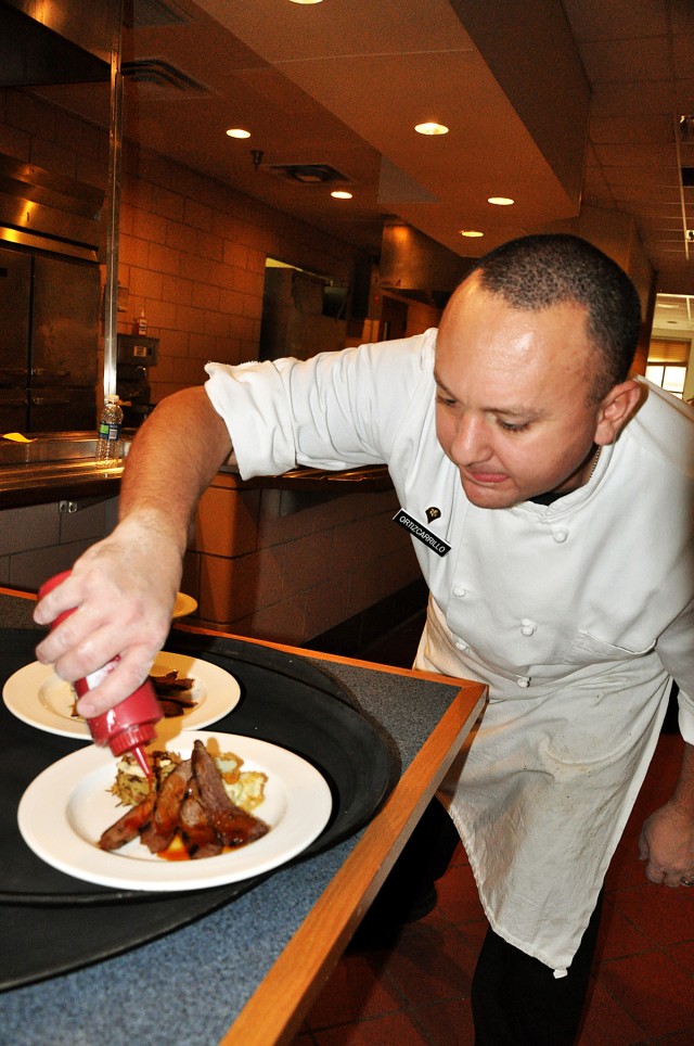 FORT HOOD, Texas- Spc. Diego Ortiz-Carrillo, a Mexico City, Mexico native, pours a special sauce over Texas sirloin during a luncheon for members of the 41st Fires Brigade held at the Fort Hood Culinary Arts Center, Jan. 20. A house salad with vinaig...