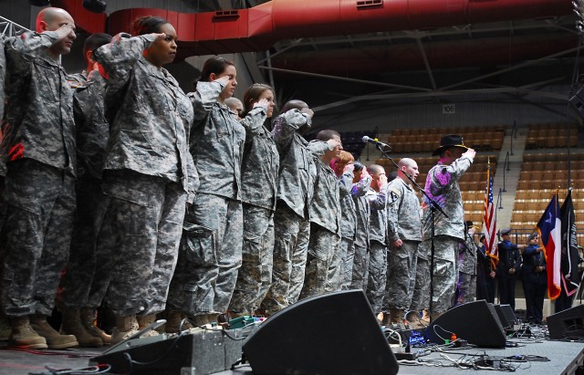 FORT HOOD, Texas - Command Sgt. Maj. Glen Vela, a native of Fort Worth, Texas, 1st Air Cavalry Brigade, 1st Cavalry Division, leads Soldiers in a salute while Spc. Douglas Livengood, of Big Spring, Texas, sings the National Anthem for the audience...