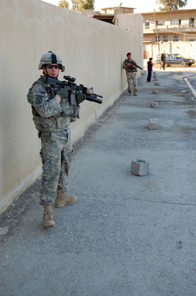 Sgt. Sean Jones, an infantryman assigned to Company B, 2nd Battalion, 7th Cavalry Regiment, 4th Advise and Assist Brigade, 1st Cavalry Division, and an Iraqi Army soldier, provide security during a partnered patrol through the city of Qara Qosh, Iraq...