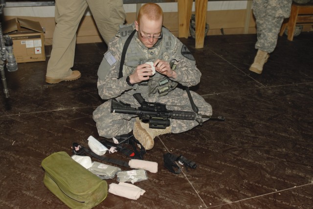 CAMP BUEHRING, Kuwait - Pfc. Adam Miller, with the Personal Security Detachment, Headquarters and Headquarters Troop, 3rd Advise and Assist Brigade, 1st Cavalry Division, prepares his first aid supplies during a medical-simulation training event, Feb...