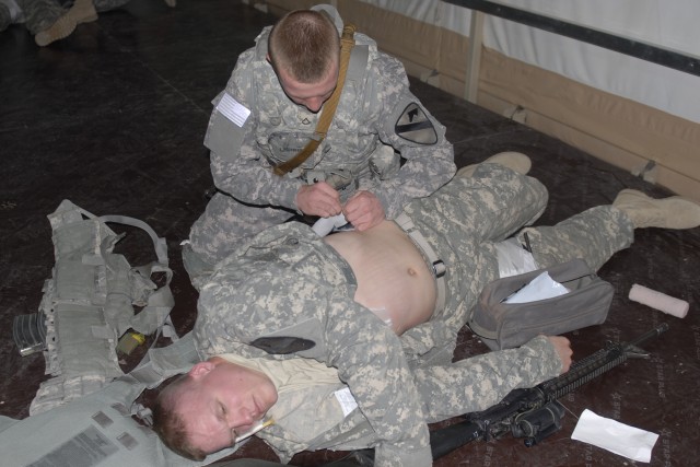 CAMP BUEHRING, Kuwait - Pfc. Tyler Meier (top) applies bandages to Pvt. Jared Heath as part of a medical-simulation training event Feb. 12. Both Soldiers are with the Personal Security Detachment, Headquarters and Headquarters Troop, 3rd Advise and A...
