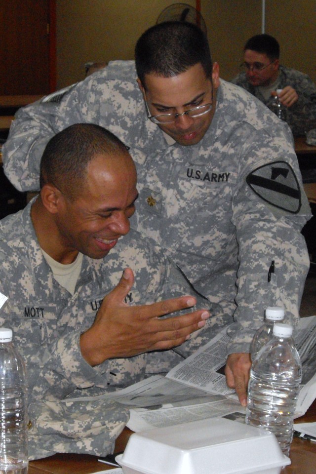 VICTORY BASE COMPLEX, Iraq - Maj. William Mott and Maj. Luis Cruz, both stability transition team members from 3rd Advise and Assist Brigade, 1st Cavalry Division, discuss an article on Iraqi current events during Stability Academy training at Victor...