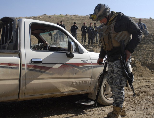 CONTINGENCY OPERATING SITE MAREZ, Iraq - With fellow policemen watching, an Iraqi policeman assigned to 3rd Federal Police Division uses a mirror to inspect a vehicle during checkpoint training at Contingency Operating Site Marez, Feb. 17, 2011. Trai...