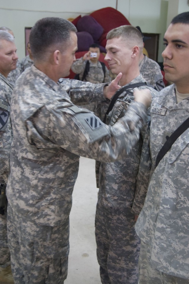 JOINT SECURITY STATION INDIA, Iraq - Maj. Gen. Daniel Allyn, commanding general of 1st Cavalry Division, presents a Combat Infantry Badge to Spc. Tyler Brinkman, during an awards ceremony at Joint Security Station India, Feb. 23, 2011. Brinkman, an i...
