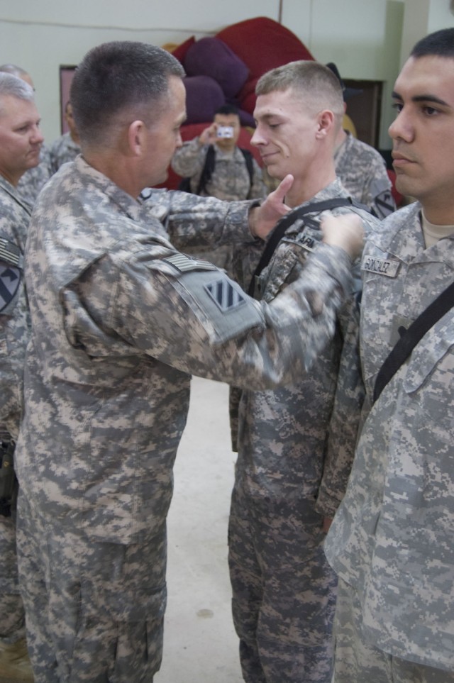 JOINT SECURITY STATION INDIA, Iraq - Maj. Gen. Daniel Allyn, commanding general of 1st Cavalry Division, presents a Combat Infantry Badge to Spc. Tyler Brinkman, during an awards ceremony at Joint Security Station India, Feb. 23, 2011. Brinkman,...