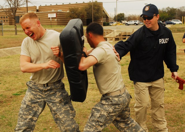 FORT HOOD, Texas - Spc. Zachary Isaac (left), a military policeman with Headquarters and Headquarters Company, 2nd Brigade Combat Team, 1st Cavalry Division, attacks a bag after being sprayed with pepper spray during a training course on Fort...