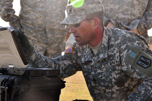 Sgt. 1st Class Randell Evans, master Raven trainer with 2nd Battalion, 20th Field Artillery Regiment, 41st Fires Brigade, loads programs onto a laptop that is synchronized with the Raven RQ-11B unmanned aerial vehicle during the 41st Fires Bde....