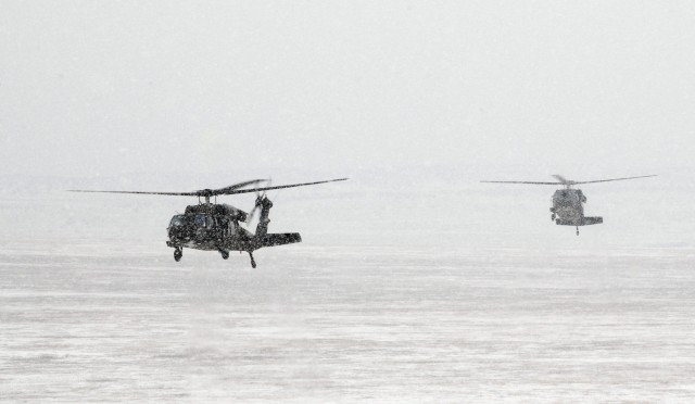 Two UH-60A Black Hawk helicopters from Task Force Spearhead 1st Air Cavalry Brigade, 1st Cavalry Division, fly through snow before visibility got too poor that a gunnery had to be canceled during high altitude, mountain environmental training near Fo...