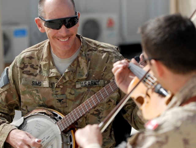 U.S. Army Col. John Sims, left, chief of information effects for ISAF Regional Command (South), and Canadian Air Force Capt. Paul Dacier, officer in charge of priority air mission requests for RC-South, play bluegrass music together at the...