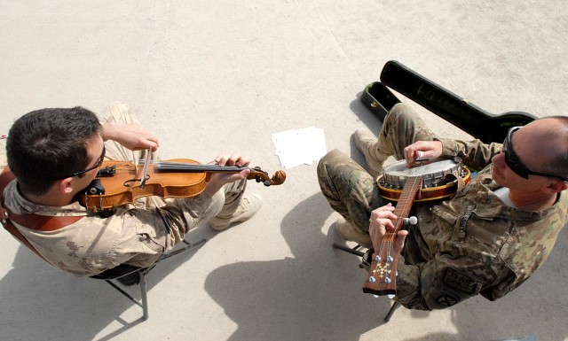 U.S. Army Col. John Sims, chief of information effects for ISAF Regional Command (South), and Canadian Air Force Capt. Paul Dacier, officer in charge of priority air mission requests for RC-South, play bluegrass music together at the RC-South...