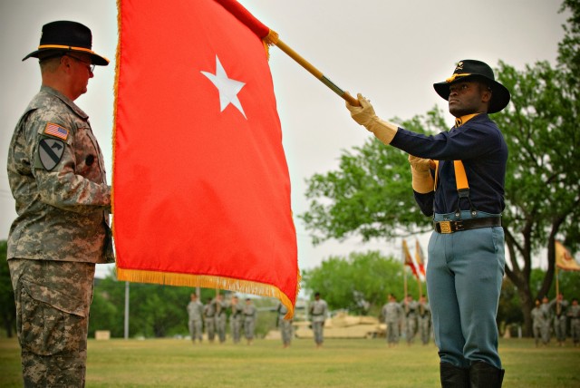 FORT HOOD, Texas-Spc. Bayee Besong (right), of Denver, Colo., an administrative assistant to the 1st Cavalry Division's command group, presents the one star flag to the Command Sgt. Maj. Rory Malloy for "uncasing." The uncasing of the one-star...