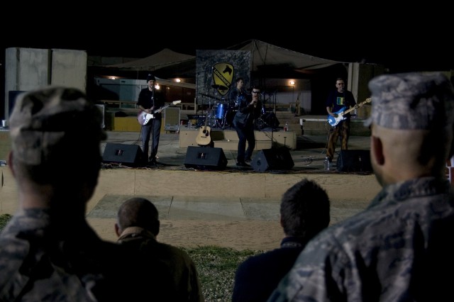 CONTINGENCY OPERATING SITE MAREZ, Iraq - Deployed service members and Department of Defense personnel watch the U2 cover band, Rattle and Hum, perform at the amphitheater on COS Marez, March 24. The rock band thanked the deployed Americans for their ...