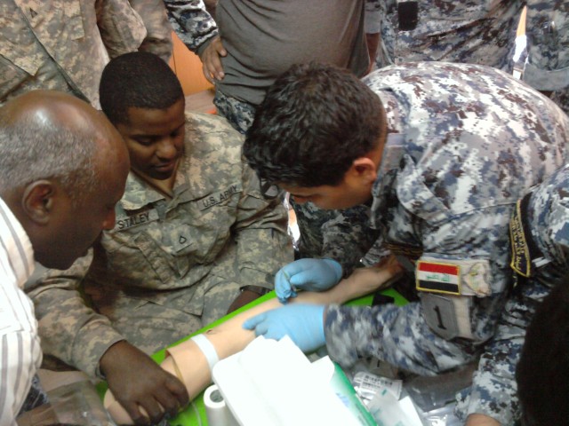 BAGHDAD, Iraq-Pfc. Dorian Staley (center), 6th Squadron, 9th Cavalry Regiment, 2nd Advise and Assist Brigade, 1st Infantry Division, United States Division - Center, watches as a member of the 4th Iraqi Federal Police practices administering an IV...